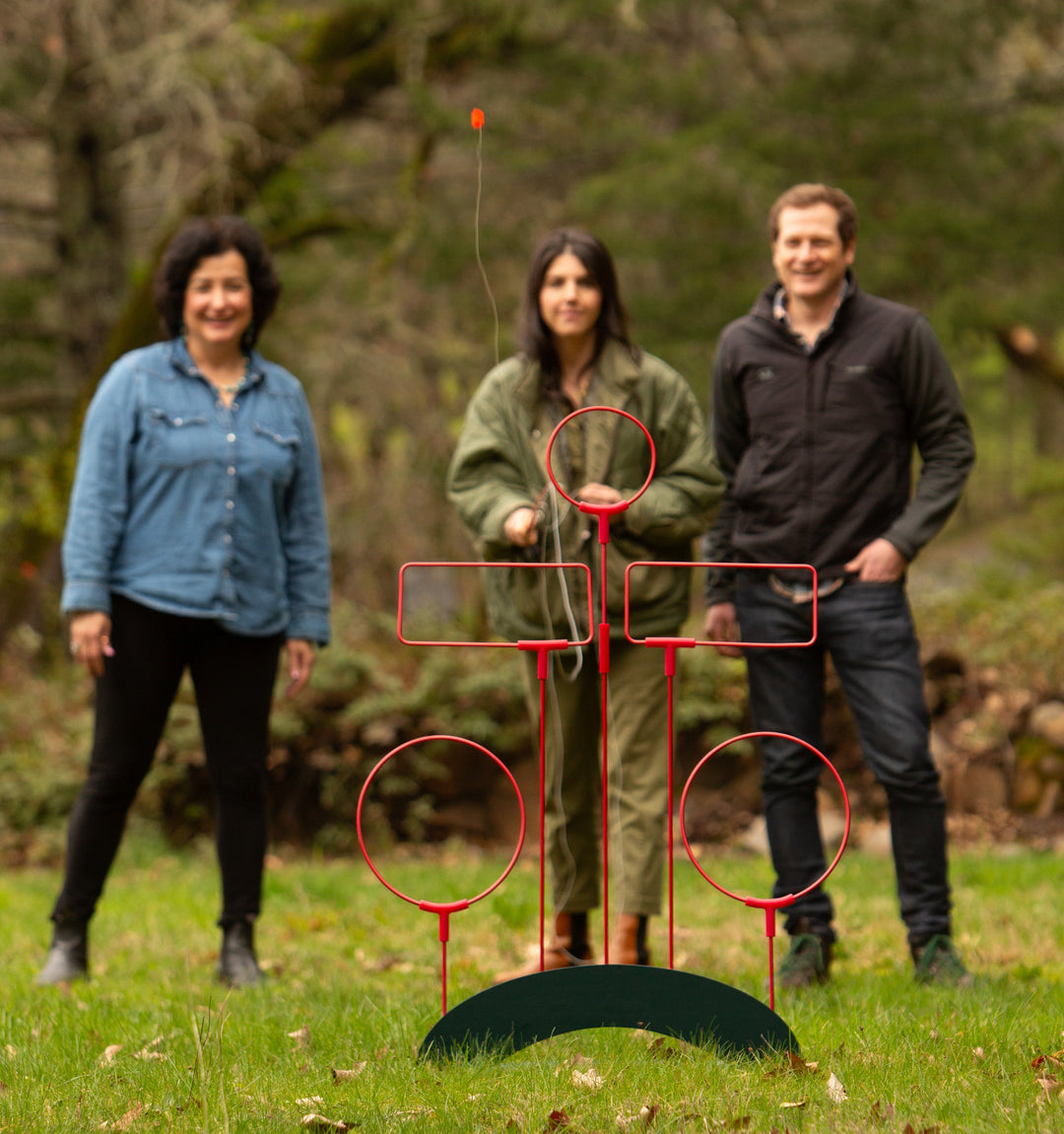 Three friends playing fly fishing yard game on lawn 